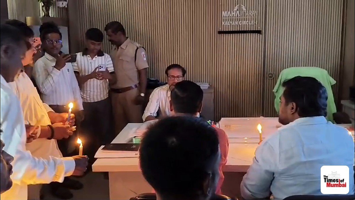 Protesters holding candles in a darkened MSEDCL office in Kalyan as an officer sits at his desk