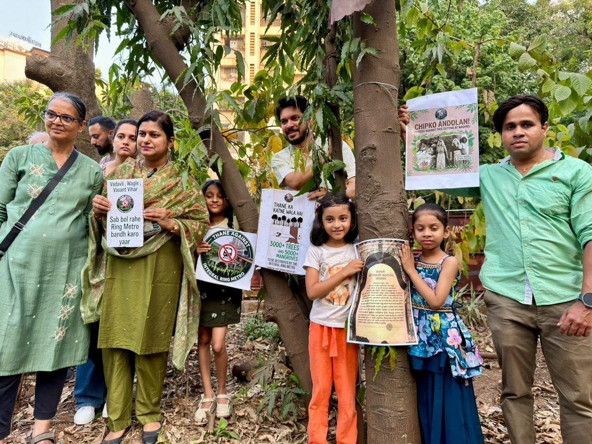 Residents and children holding anti-Ring Metro placards beside trees at Waghbil, Thane